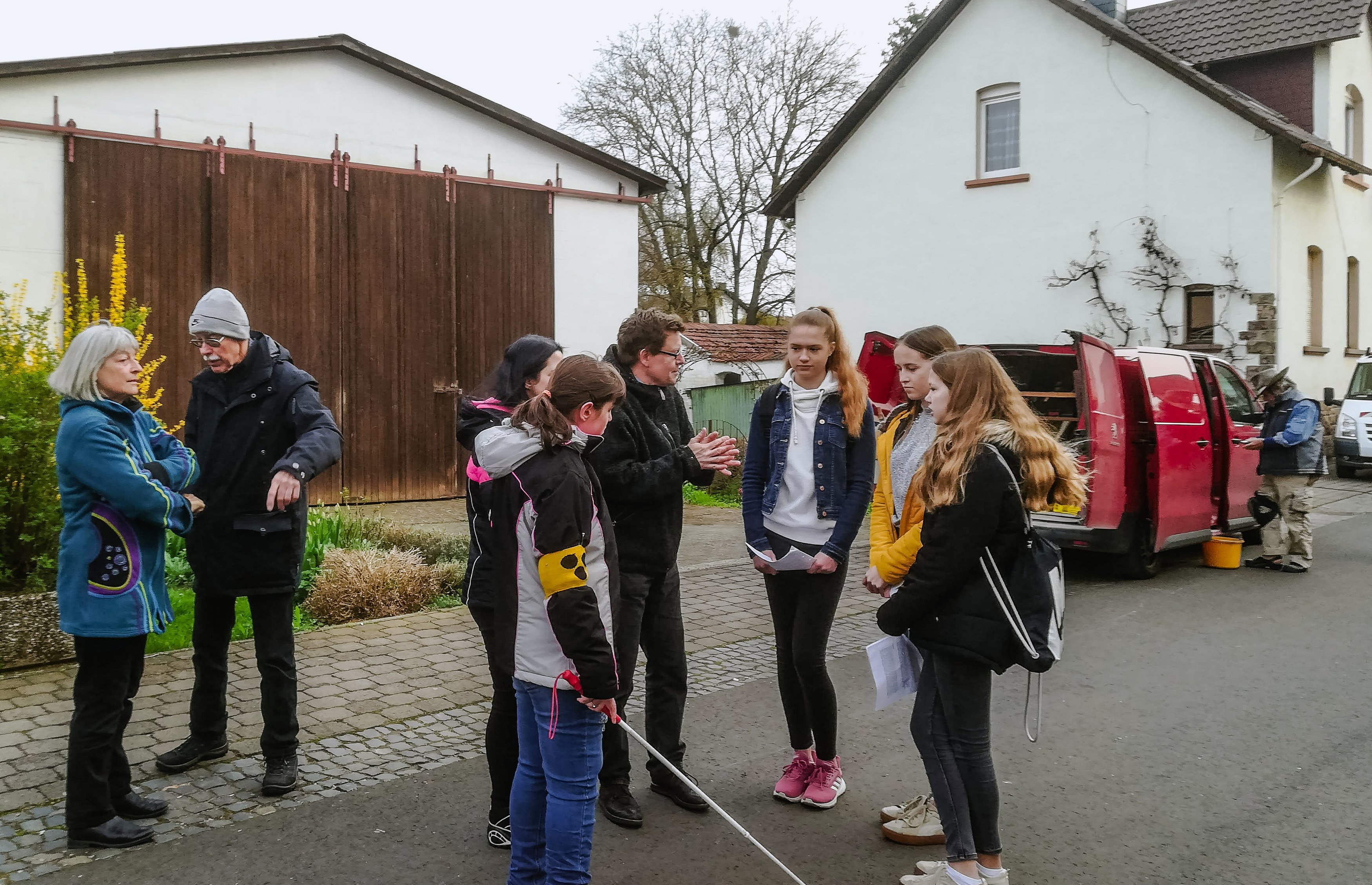 Eine Gruppe Jugendlicher und Erwachsener steht auf der Straße vor Häusern