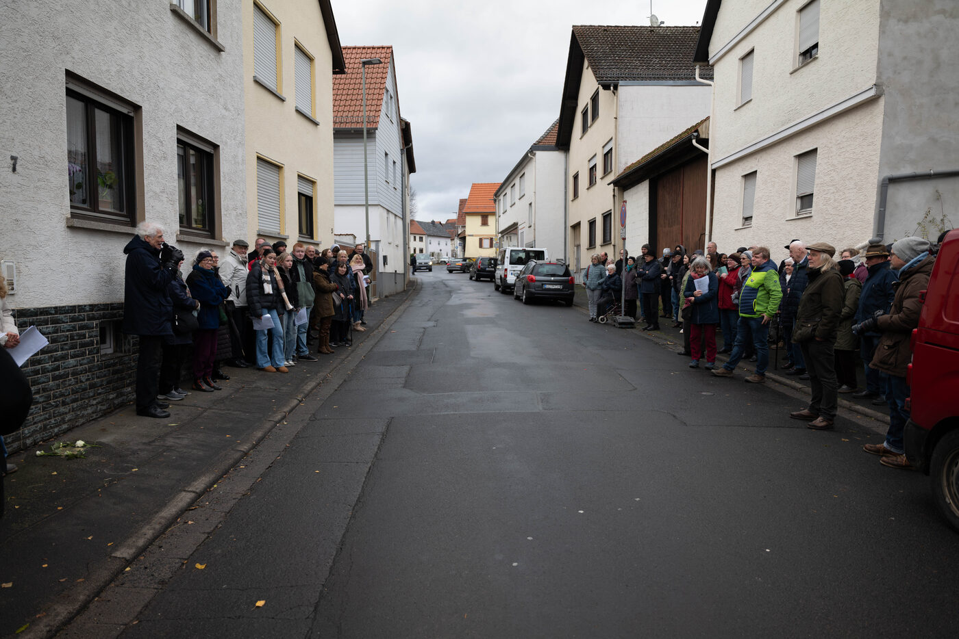 Menschen säumen beide Seiten einer Dorfstraße.