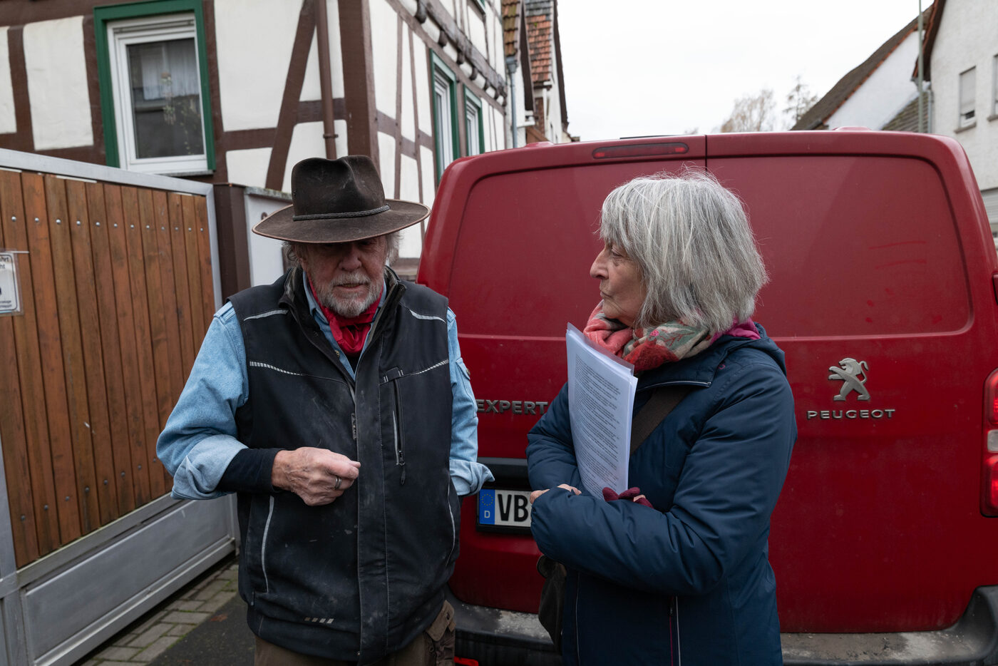 Gunter Demnig und eine Frau stehen nebeneinander vor dem roten Transporter.