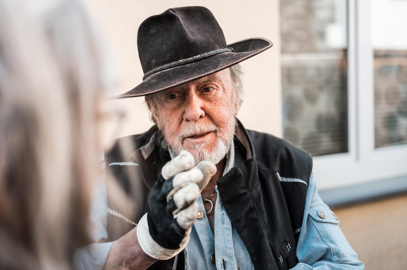 Gunter Demnig mit Hut und Arbeitshandschuhen im Gespräch.